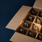 DTC packaging - Korpack - Packaging Solutions for Complex Businesses Open cardboard box with dozen glass bottles in compartments, capped with metal caps as shipping packing.