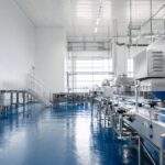USDA meat packaging - Korpack - Packaging Solutions for Complex Businesses Industrial food processing plant with stainless steel equipment on a blue epoxy floor, conveying a clean, high-tech production line.