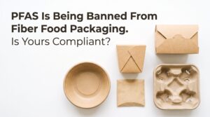 pfas free - Korpack - Packaging Solutions for Complex Businesses Bold headline about PFAS ban on fiber food packaging with scattered kraft paper boxes, cups, and a muffin tray on a white background.