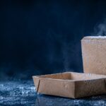 ChatGPT Image Aug 6 2026 10_52_19 AM - Korpack - Packaging Solutions for Complex Businesses Two frosty cardboard boxes—one open tray in front, one upright—on a icy, cold surface with fog in the background.