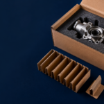 dunnage - Korpack - Packaging Solutions for Complex Businesses Metal mechanical component nestled in foam padding inside an open cardboard box, with protective packing separators nearby.