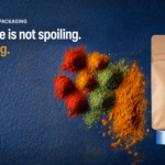 spice packaging - Korpack - Packaging Solutions for Complex Businesses Spices in red, orange, green, and yellow spill from a kraft pouch onto a dark blue textured surface with the headline: “Your spice is not spoiling. It is fading.”